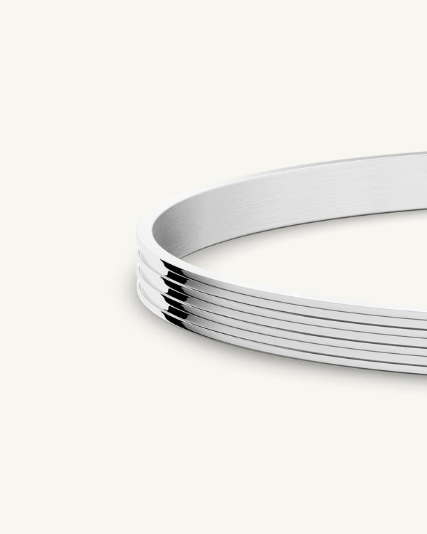 A polished stainless steel bangle in silver from Waldor & Co. One size. The model is Avant Bangle Polished