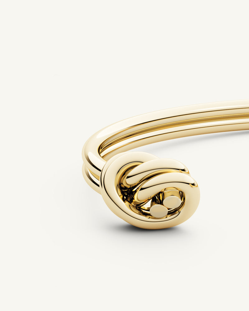 A Bangle in 14k-gold plated 316L stainless steel from Waldor & Co. One size. The model is Dual Knot Twin Bangle Polished.