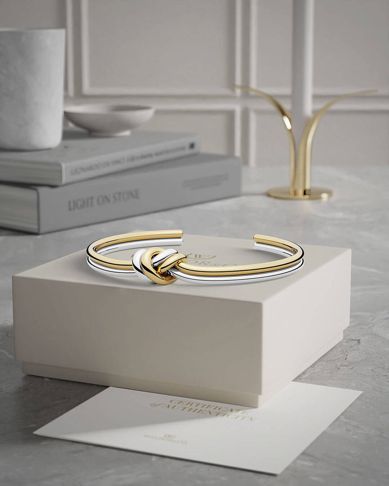 A Bangle in 14k-gold plated and silver polished 316L stainless steel from Waldor & Co. One size. The model is Dual Knot Bangle Polished.